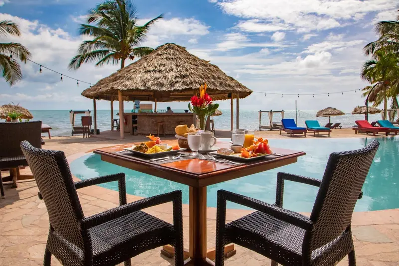 Une table dressée pour le petit-déjeuner près d'une piscine et d'un bar en bord de mer.