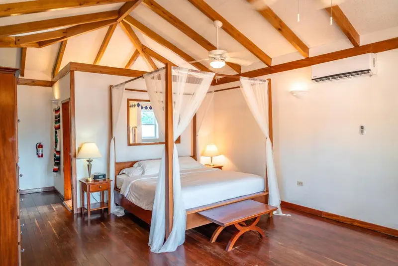 Une chambre lumineuse avec un lit à baldaquin et un parquet en bois.