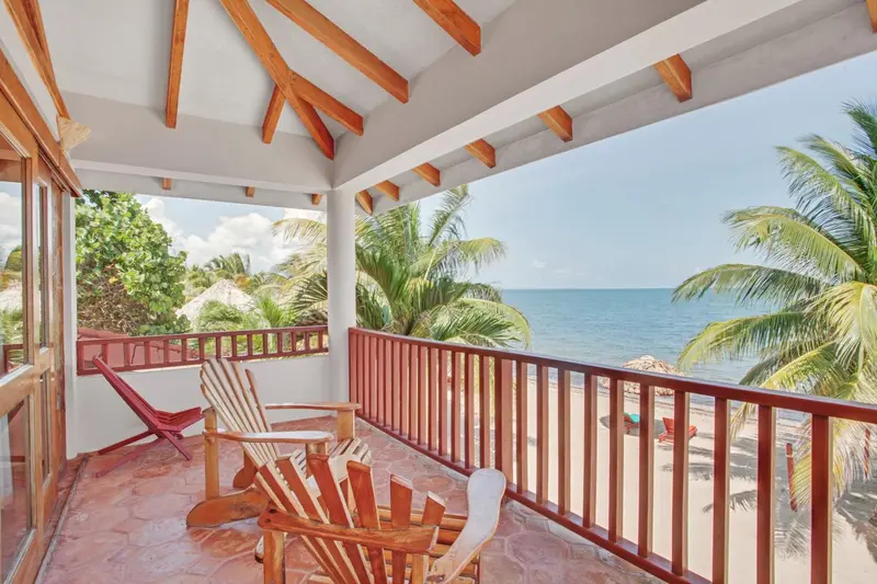 Terrasse en bois avec mobilier d'extérieur donnant sur une plage tropicale.