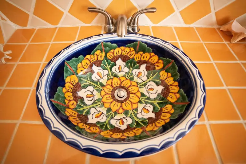 Lavabo décoré de motifs floraux sur fond de carrelage orange.