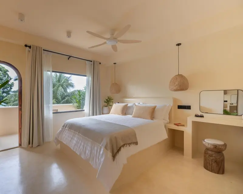 Une chambre lumineuse avec un grand lit et une vue sur la végétation.