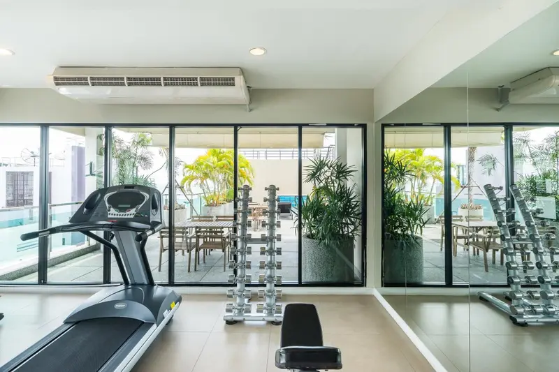 Une salle de sport lumineuse avec des équipements de musculation et une vue sur une terrasse.