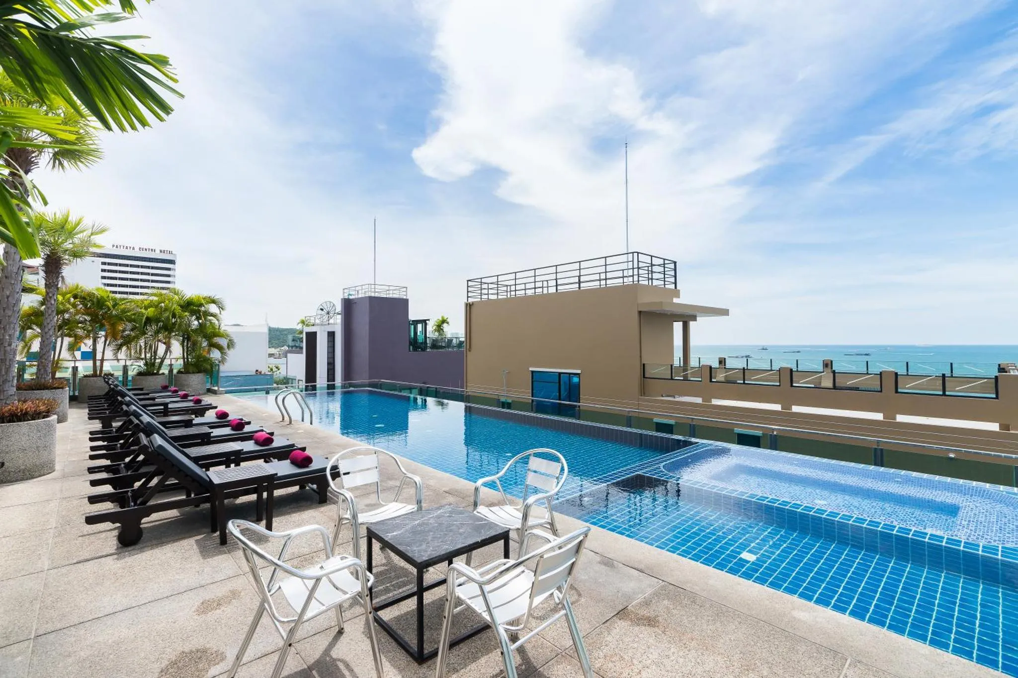 Transats et tables basses bordent une piscine rectangulaire sur un toit-terrasse.