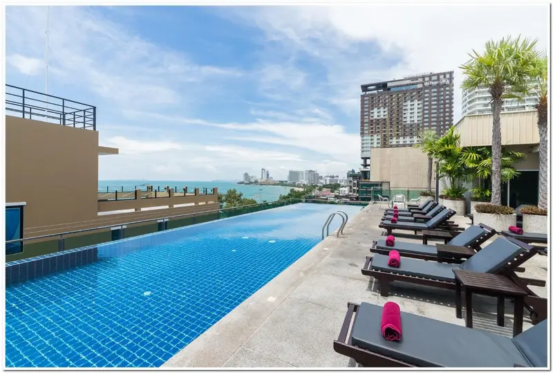 Une piscine bleue bordée de transats sur une terrasse ensoleillée.