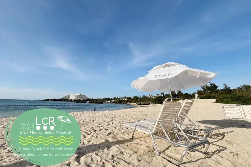 Transats blancs disposés sur une plage de sable fin sous des parasols.