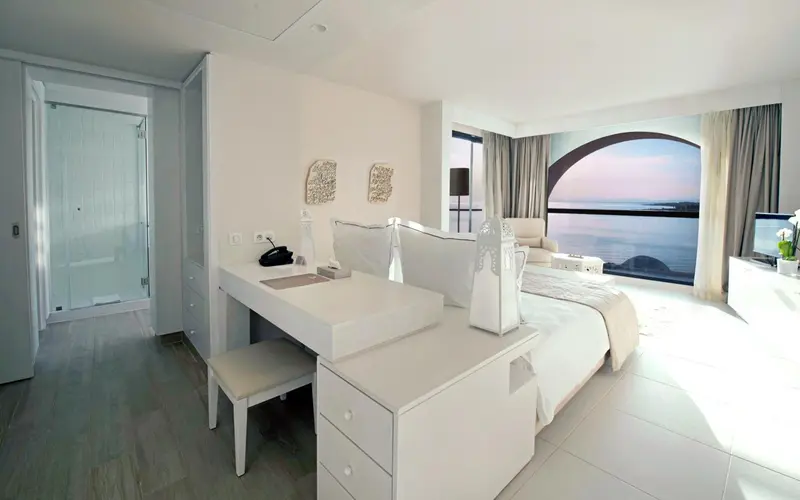 Chambre lumineuse avec un grand lit et vue sur la mer.