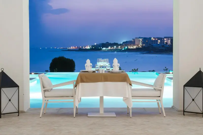 Une table dressée pour deux en extérieur, face à la mer illuminée.