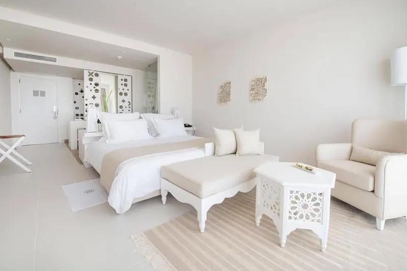 Chambre lumineuse avec un lit double et un coin salon.