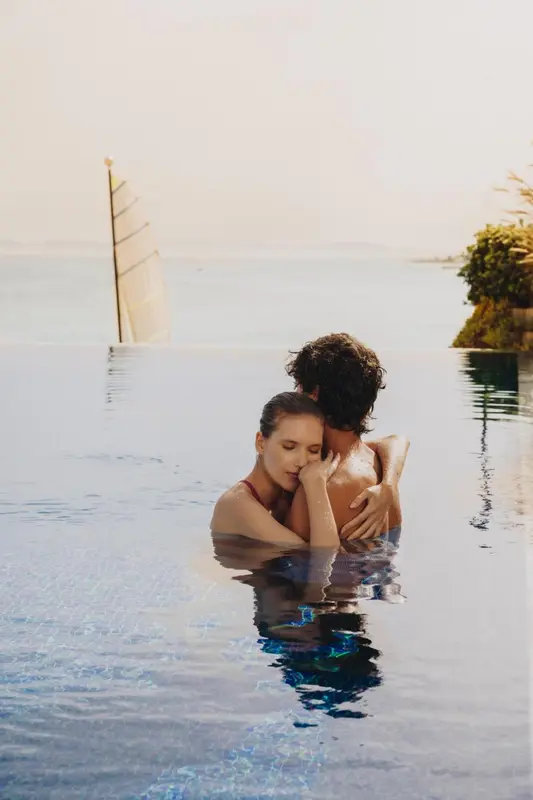 Un couple se tient dans l'eau d'une piscine, se regardant tendrement.