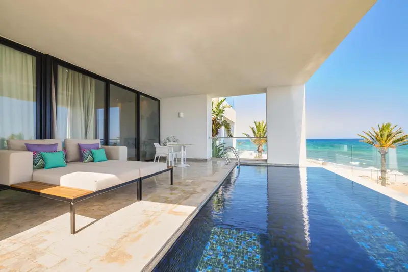 Salon d'intérieur s'ouvrant sur une terrasse avec piscine et vue sur la mer.