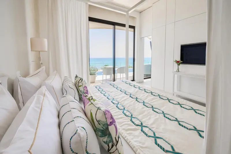 Une chambre lumineuse avec un grand lit et une vue sur la mer.