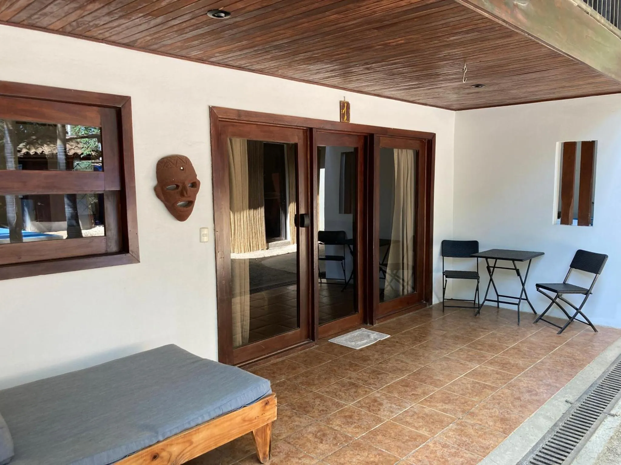 Terrasse ombragée avec mobilier de jardin et accès à une pièce intérieure.