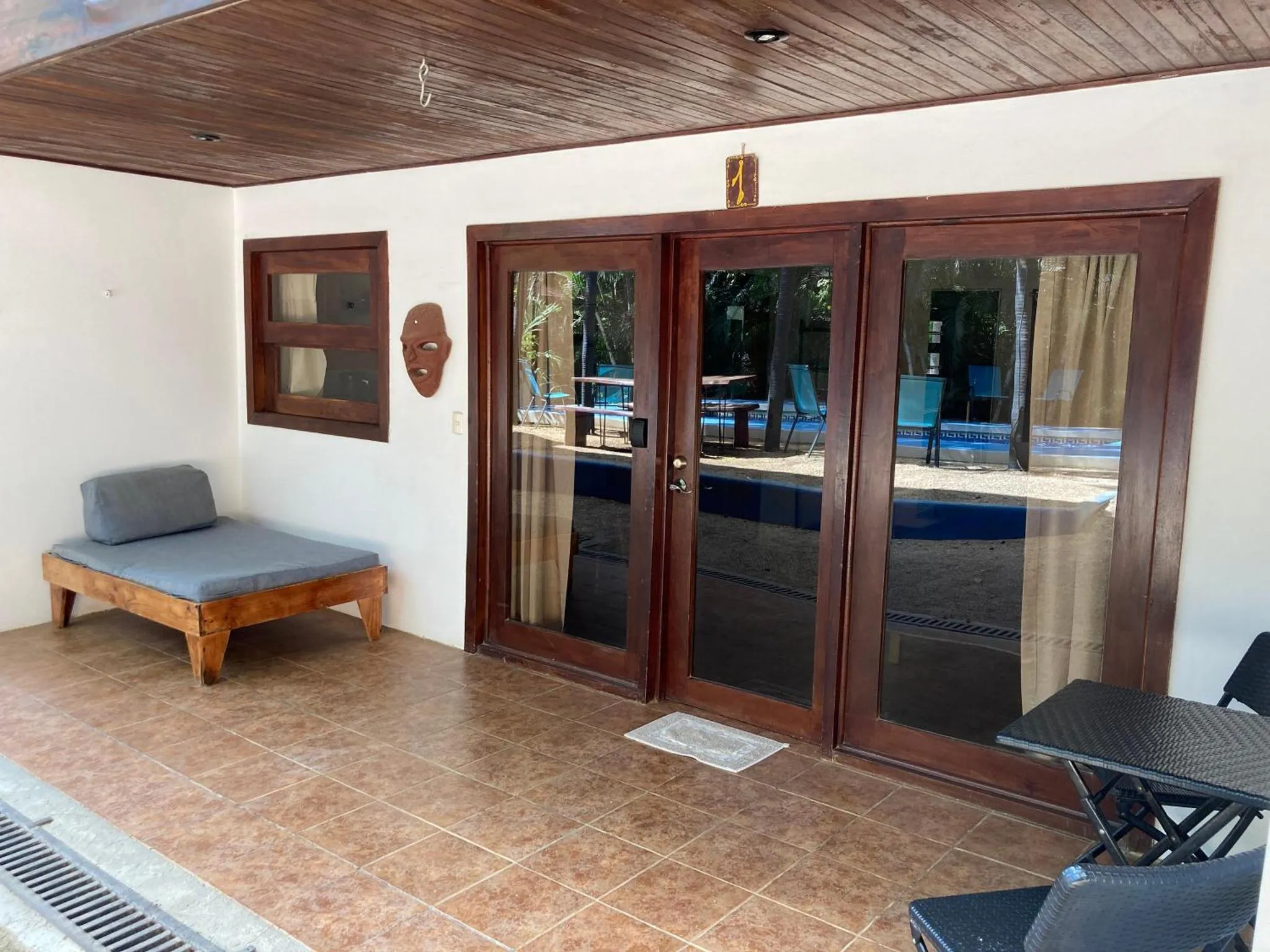 Terrasse ombragée avec assise et table devant une porte vitrée.