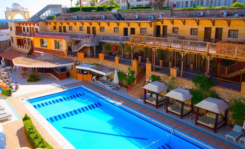 Vue aérienne d'une piscine et de terrasses ensoleillées avec des parasols.