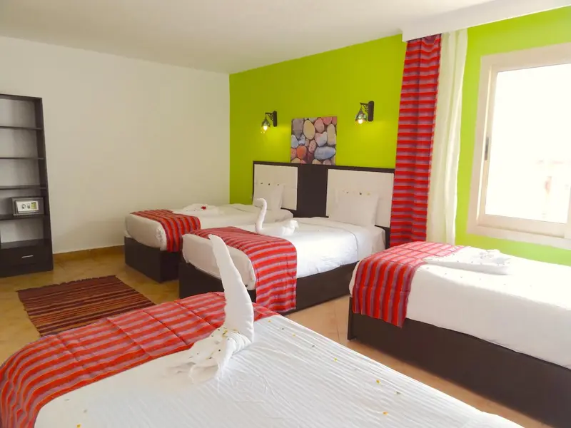 Une chambre lumineuse avec deux lits simples décorés de serviettes en forme de cygnes.