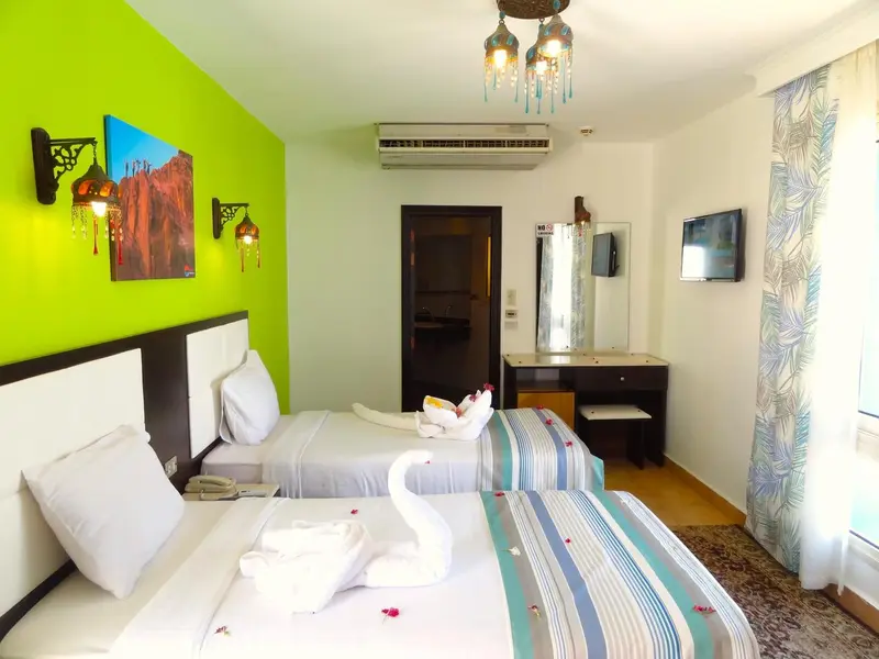 Chambre lumineuse avec deux lits simples et décoration murale colorée.