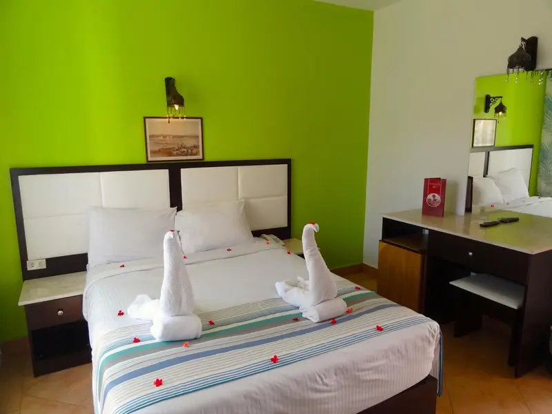 Une chambre lumineuse avec un grand lit décoré de serviettes en forme de cygnes.