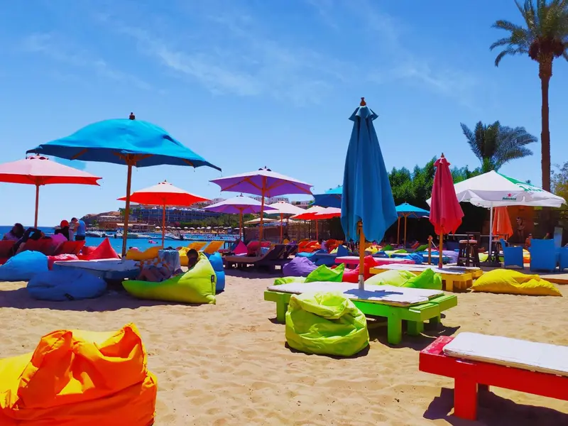 Plages de sable fin avec des transats colorés et des parasols sous un ciel bleu.