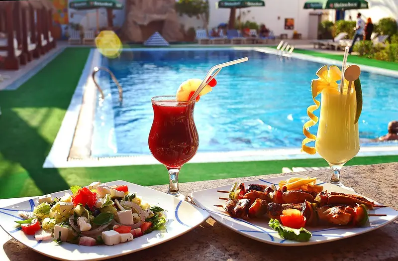 Des plats et des boissons colorées sont servis en bord de piscine.