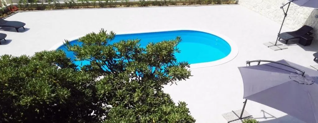 Une piscine rectangulaire entourée de transats et de parasols.
