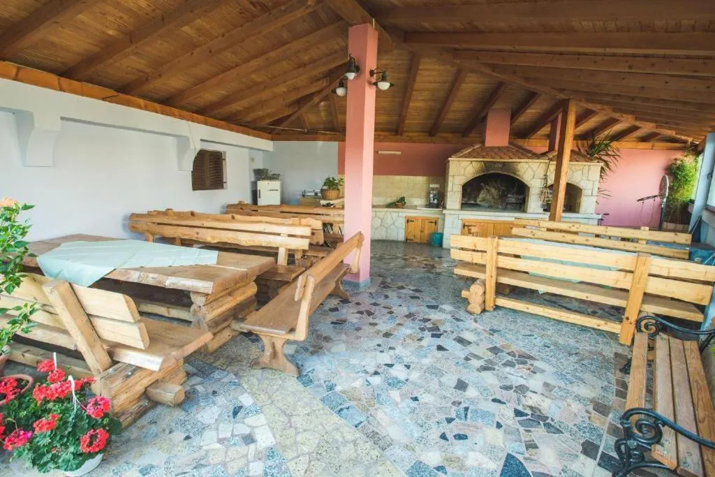 Espace de restauration extérieur avec tables en bois et barbecue en pierre.