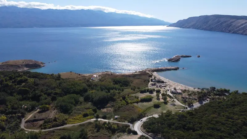 Vue aérienne d'une côte rocheuse et d'une plage ensoleillée.