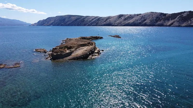 Vue aérienne d'îlots rocheux dans une mer bleue scintillante.