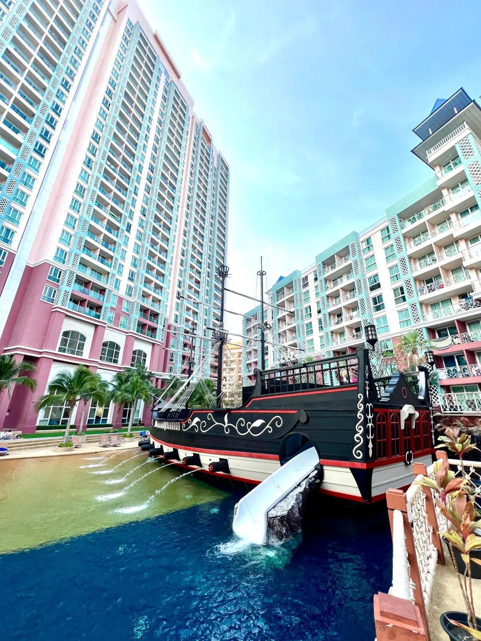 Un bâtiment coloré se dresse à côté d'une réplique de bateau pirate dans une piscine.