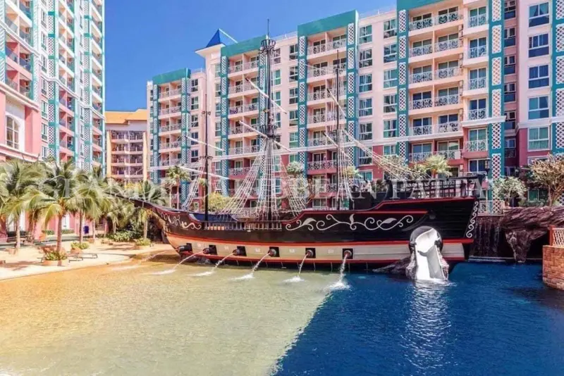 Un navire pirate orne un bassin d'eau turquoise devant un bâtiment coloré.
