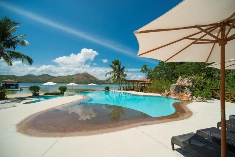 Une piscine bleue bordée d'une terrasse ensoleillée avec des transats.
