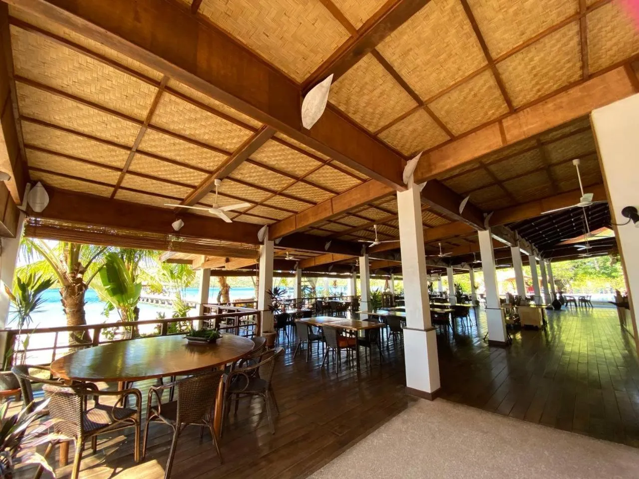 Une salle ouverte sur la mer, avec des tables et des chaises en bois.