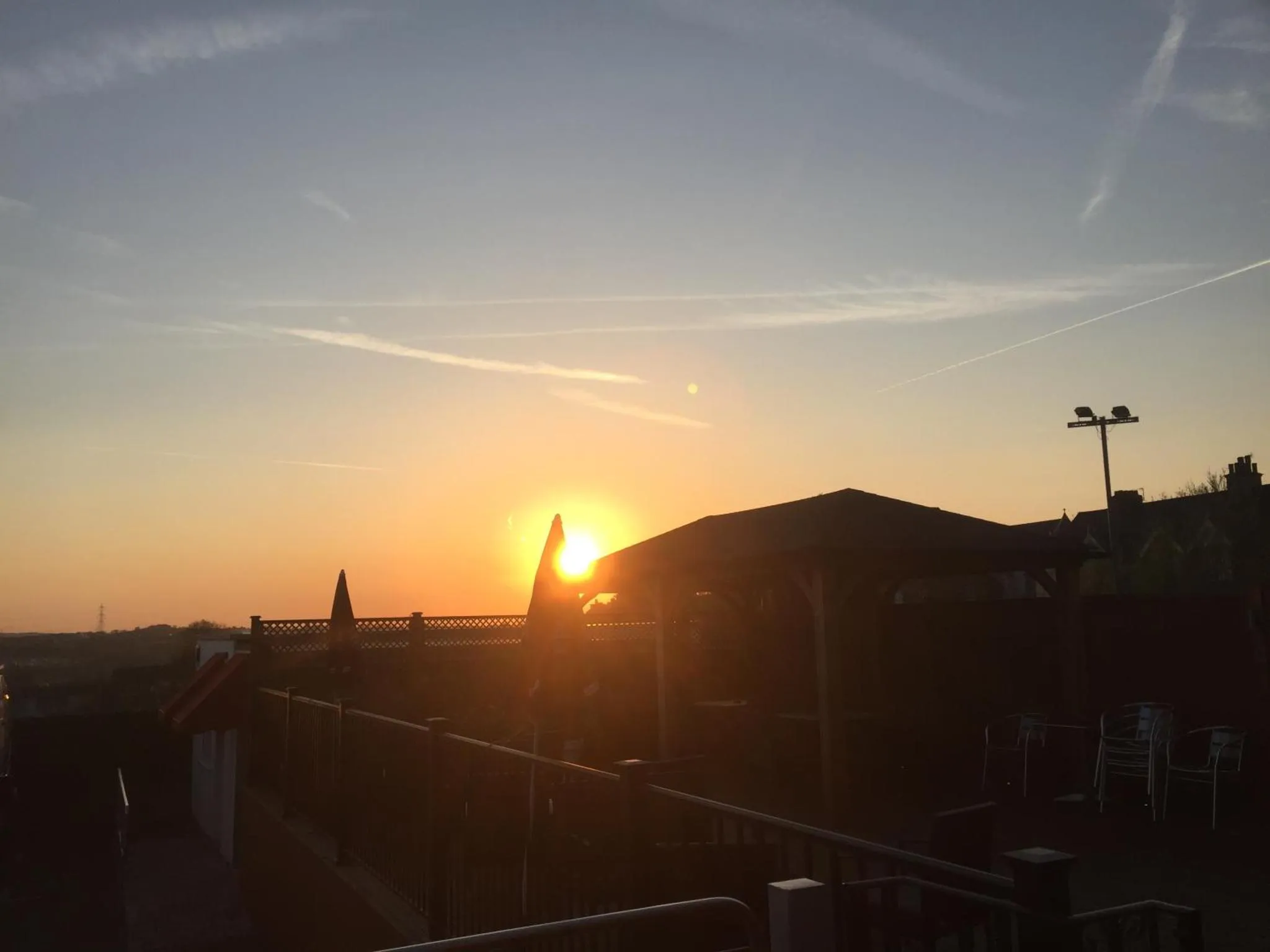 Coucher de soleil sur un toit avec des chaises et des tables.