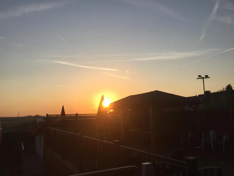 Coucher de soleil sur un toit avec des chaises et des tables.