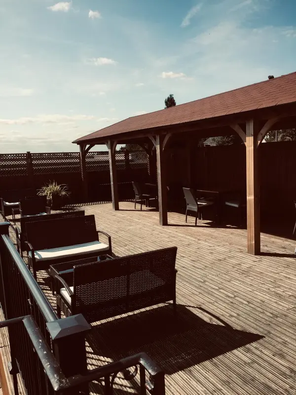 Terrasse ombragée avec mobilier de jardin en rotin.