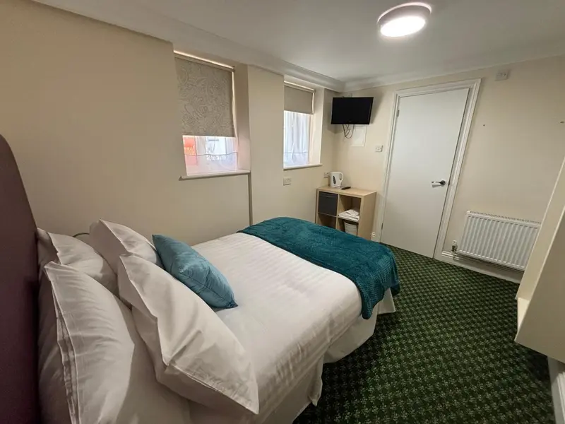 Une chambre avec un lit fait et une télévision murale.