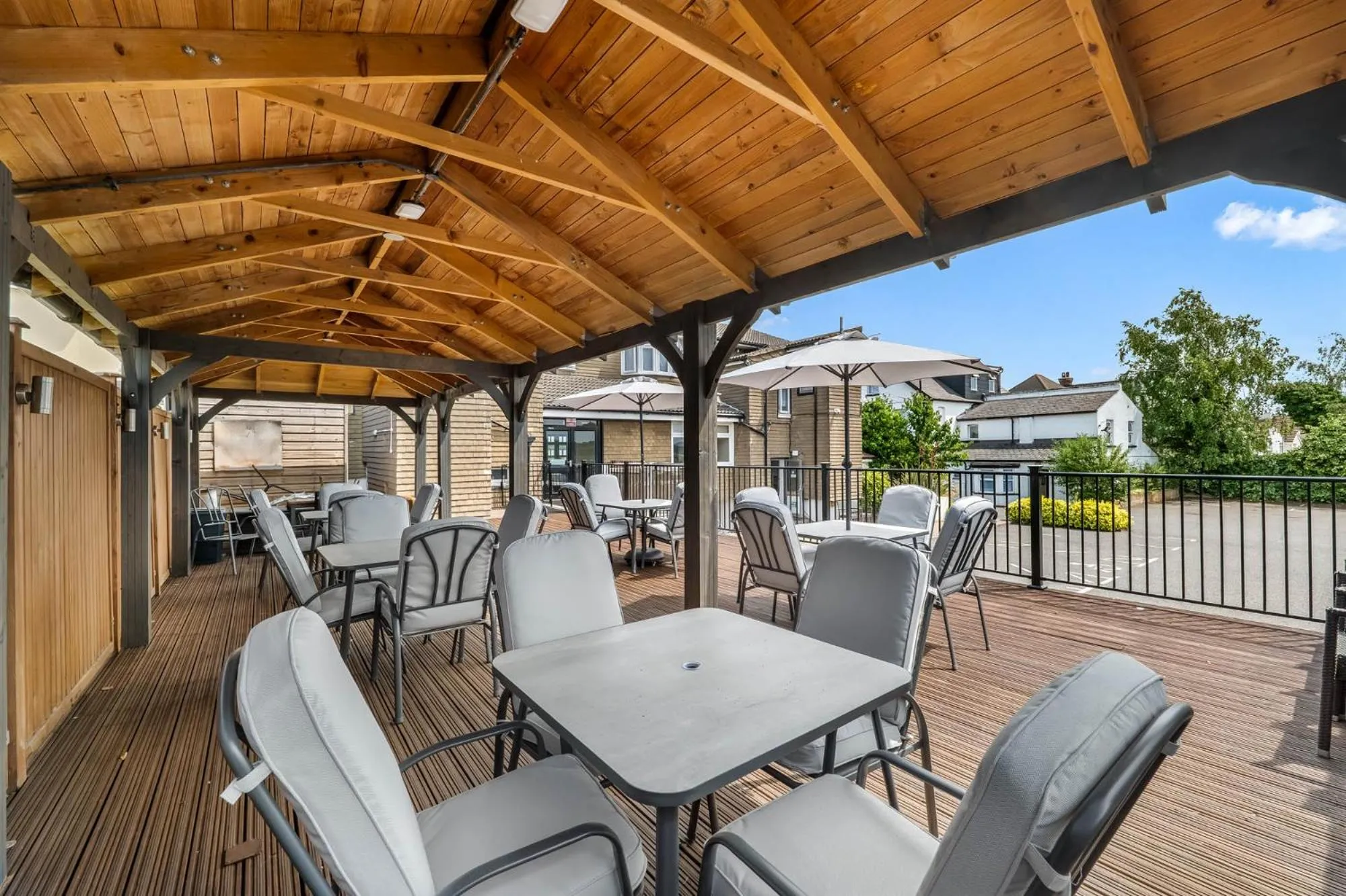 Terrasse ombragée avec tables et chaises en bois et métal.