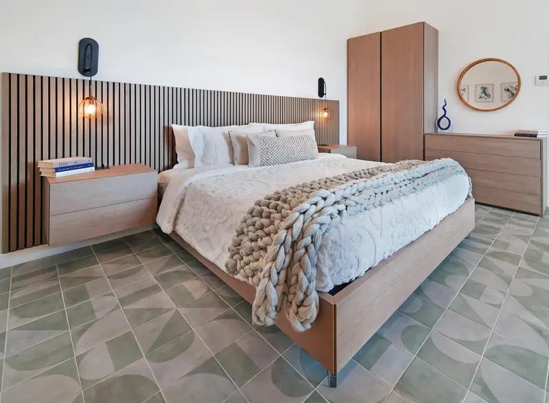 Une chambre lumineuse avec un grand lit recouvert d'une couverture texturée.