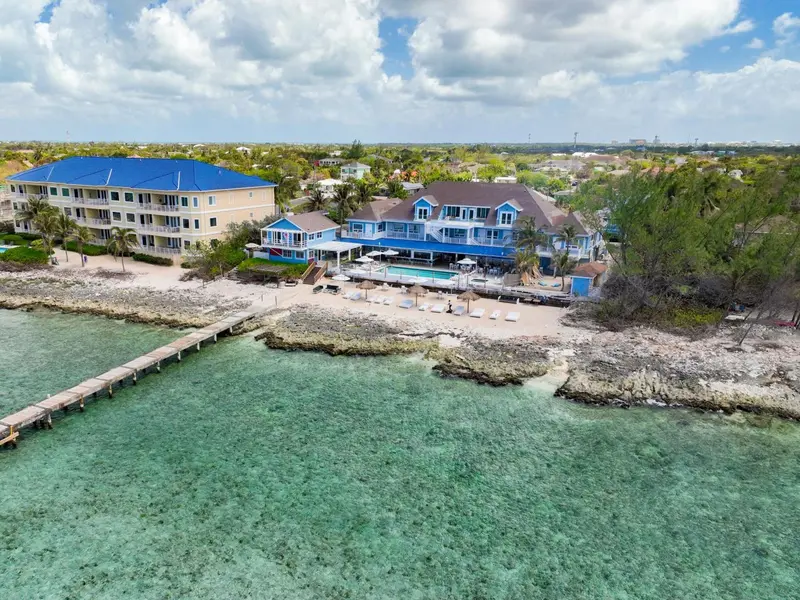 Vue aérienne d'un complexe hôtelier au bord de l'eau avec une plage et un ponton.