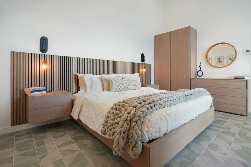 Une chambre lumineuse avec un grand lit recouvert d'une couverture texturée.