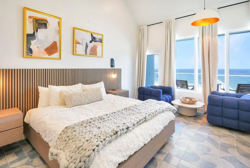 Une chambre lumineuse avec un grand lit et un coin salon donnant sur la mer.