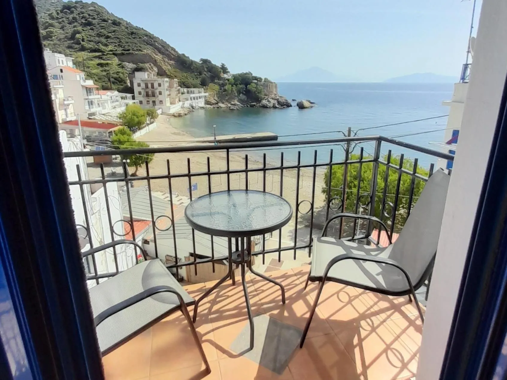 Une terrasse avec table et chaises offre une vue sur la mer et le littoral.