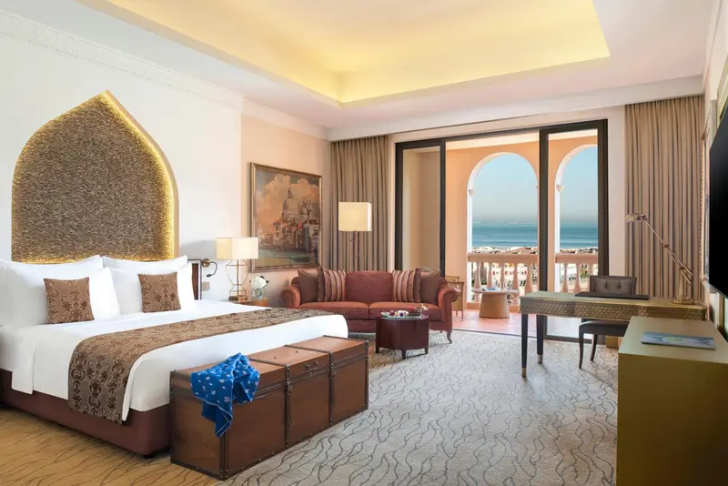 Une chambre lumineuse avec un grand lit et un accès à un balcon donnant sur la mer.