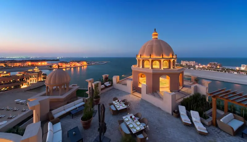 Terrasse avec mobilier d'extérieur et vue sur la mer au crépuscule.