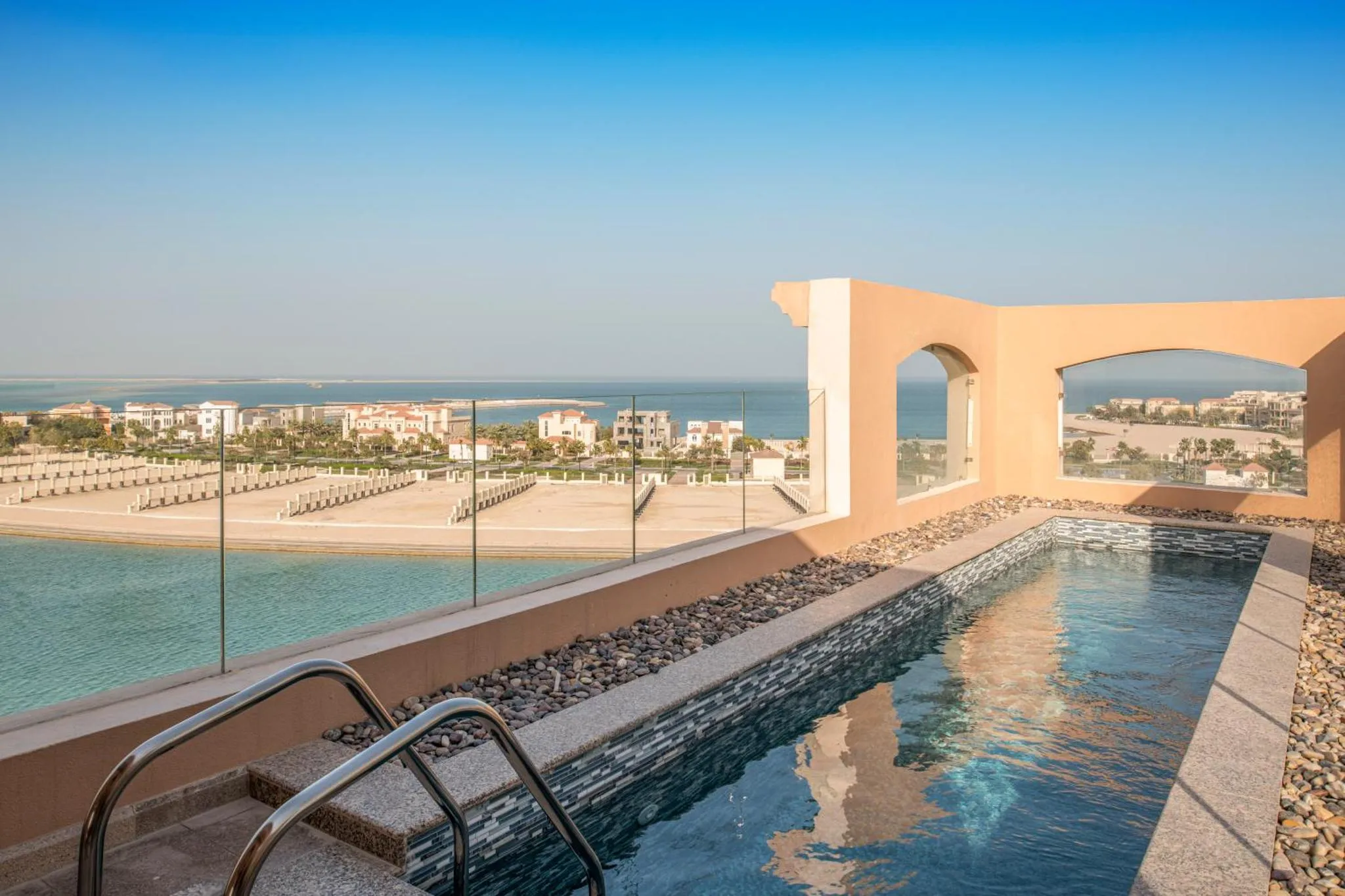 Une petite piscine sur une terrasse avec vue sur la mer et la ville.