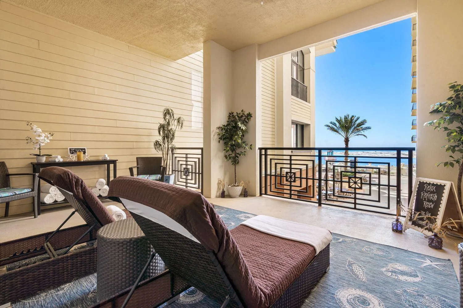 Espace de détente extérieur avec mobilier en rotin et vue sur la mer.