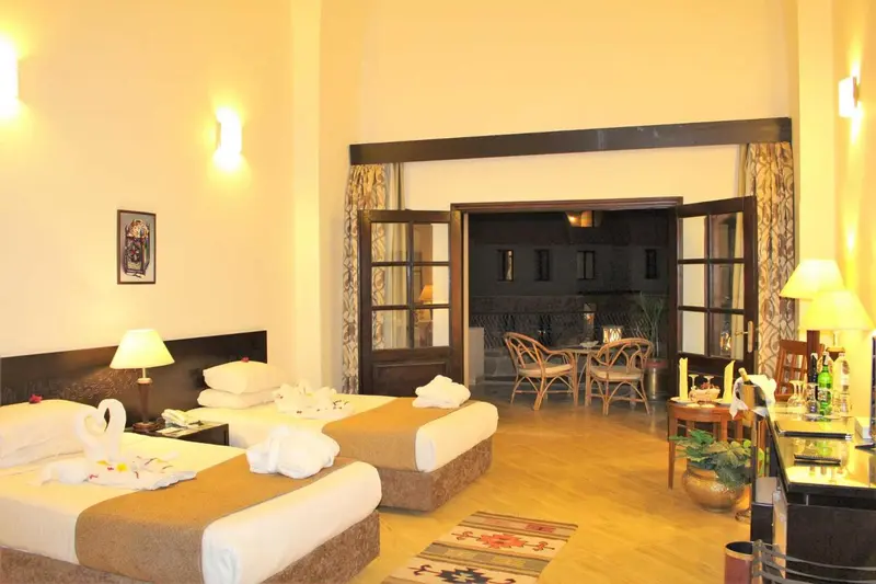 Une chambre lumineuse avec deux lits et un coin repas.