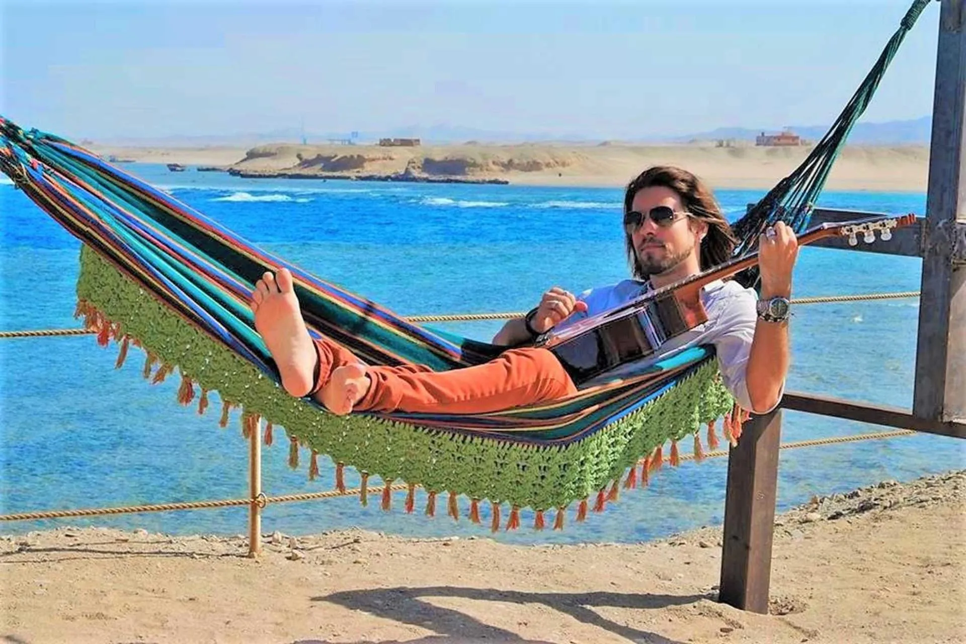 Un homme se détend dans un hamac face à la mer.