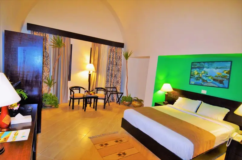Une chambre lumineuse avec un grand lit et un coin repas.