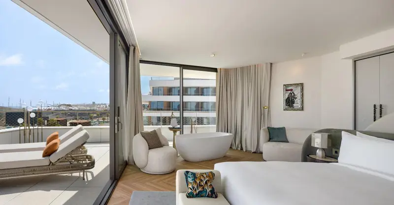 Une chambre lumineuse s'ouvre sur une terrasse avec vue sur la ville.