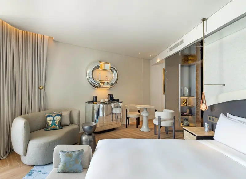 Une chambre lumineuse avec un canapé et une table basse près d'un lit.